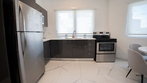 A modern kitchen with a stainless steel refrigerator, a built-in oven, and a window above the sink.