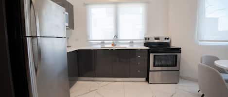 A modern kitchen with a stainless steel refrigerator, a built-in oven, and a window above the sink.