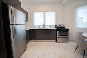 Una cocina moderna con un refrigerador de acero inoxidable, un horno empotrado y una ventana sobre el lavamanos.
