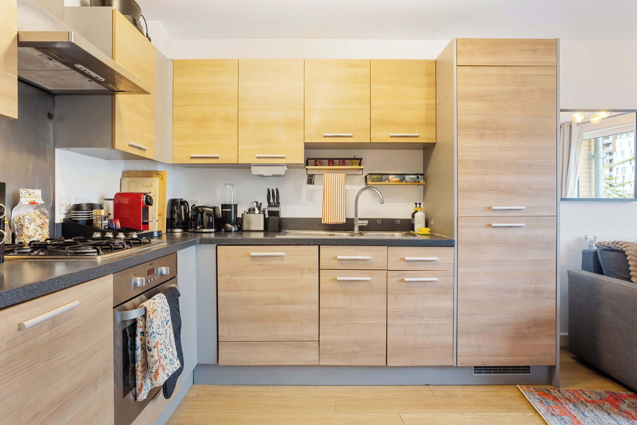 A modern kitchen with wooden cabinets, a built-in oven, and a stainless steel range hood.