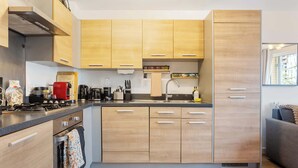 A modern kitchen with wooden cabinets, a built-in oven, and a stainless steel range hood.