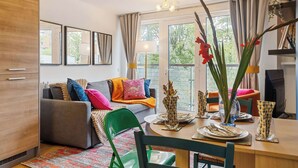 A modern living room with a sofa, dining table, chairs, and a TV.