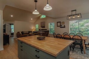 A modern kitchen with a central island, dining area with chairs, and a sofa. - NEW hot tub at this escape for 8! (Ashford)
