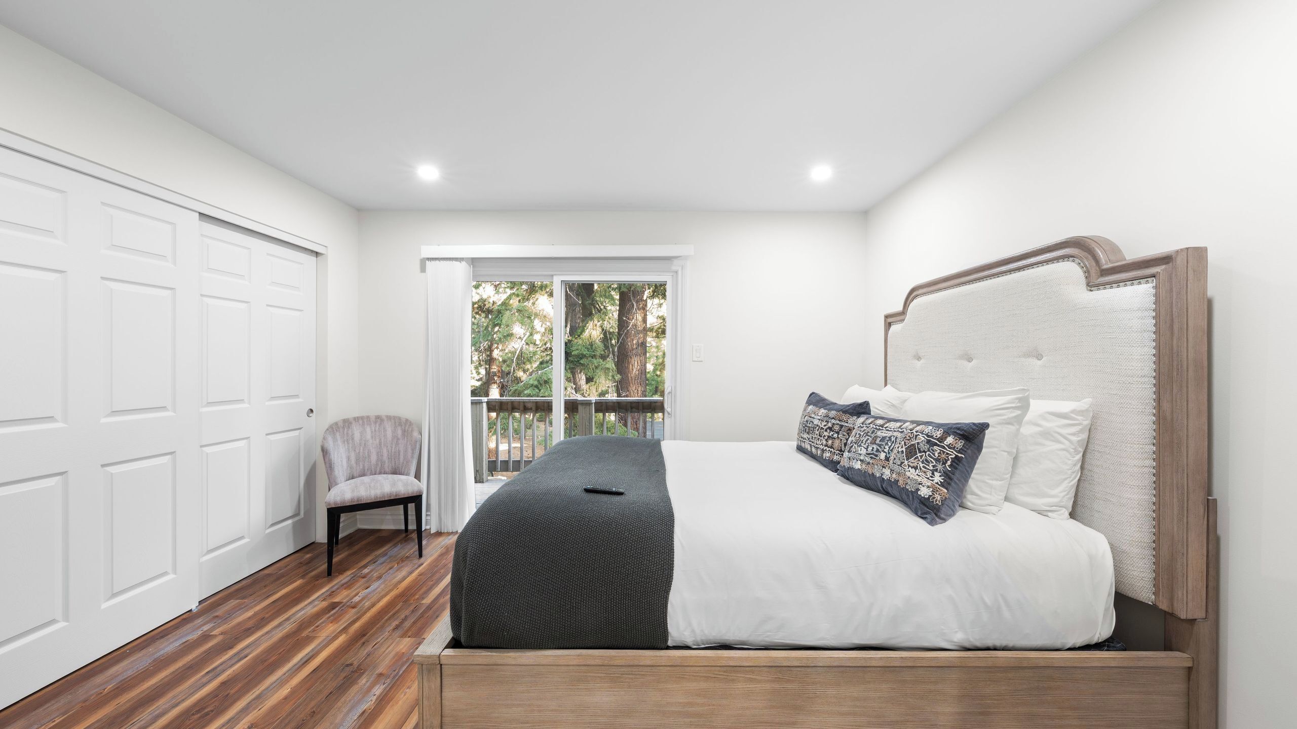A bedroom with a bed, a chair, a sliding glass door, and a white garage door.