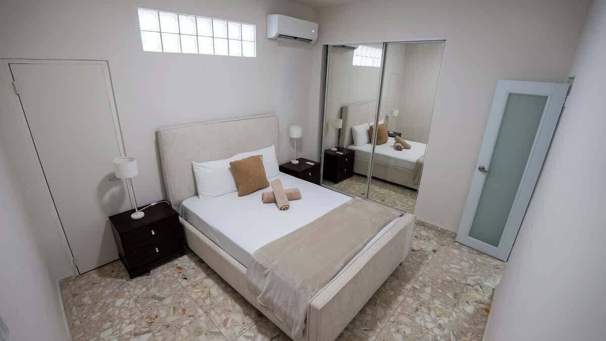 Une chambre à coucher avec un lit, des tables de chevet, un miroir et une armoire.