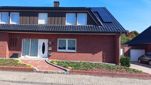 A two-story house with a brick facade, a tiled roof, and a small front garden. - Comfortable accommodation in a cozy atmosphere for you and your dog. (Neuenkirchen)