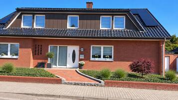 Een tweelaags huis met een bakstenen gevel, een hoofdentree en een oprit.