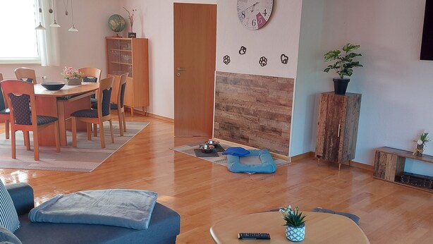 A modern living room with a sofa, coffee table, and a dining area with chairs and a table. - Comfortable accommodation in a cozy atmosphere for you and your dog. (Neuenkirchen)