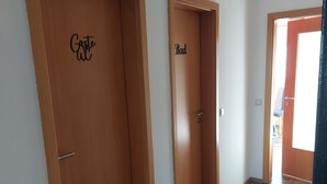 A hallway with two wooden doors, one labeled "Guest WC" and the other "Bad." - Comfortable accommodation in a cozy atmosphere for you and your dog. (Neuenkirchen)