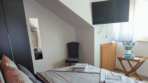 A bedroom with a bed, a chair, a TV, and a small table with a sign. - Comfortable accommodation in a cozy atmosphere for you and your dog. (Neuenkirchen)