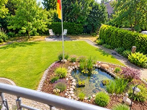 A well-maintained garden with a pond, seating area, and flag. - "Cozy 'Agnes' Vacation Rental—Dog-Friendly & Comfortable" (Neuenkirchen)