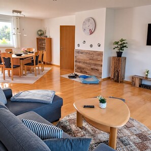 Un salon moderne comprenant un canapé, une table basse et un coin repas avec des chaises et une table.