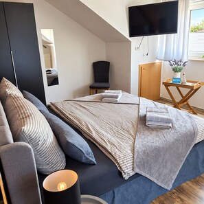 A modern bedroom with a bed, a chair, a TV, and a small table with a plant. - "Cozy 'Agnes' Vacation Rental—Dog-Friendly & Comfortable" (Neuenkirchen)