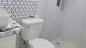 A bathroom with a toilet, a sink, and a shower enclosure.