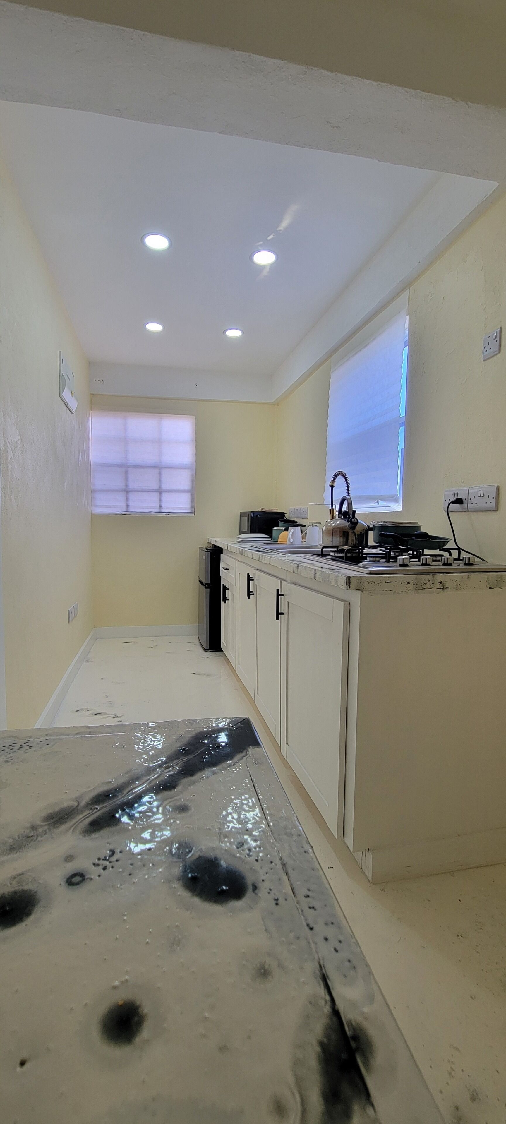 A kitchen with a white countertop, a stove, and a window with blinds.