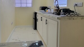 A kitchen with a white countertop, a stove, and a window with blinds.