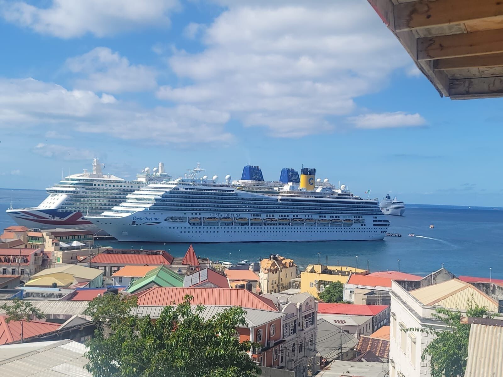 A large cruise ship docked at a port with colorful buildings in the foreground.