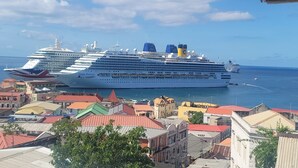 A large cruise ship docked at a port with colorful buildings in the foreground.