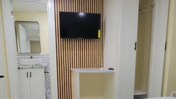 Une chambre d’hôtel avec un grand lit, un téléviseur fixé au mur, un miroir et une armoire.