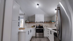 Una cocina moderna con armarios blancos, electrodomésticos de acero inoxidable y encimera de madera.