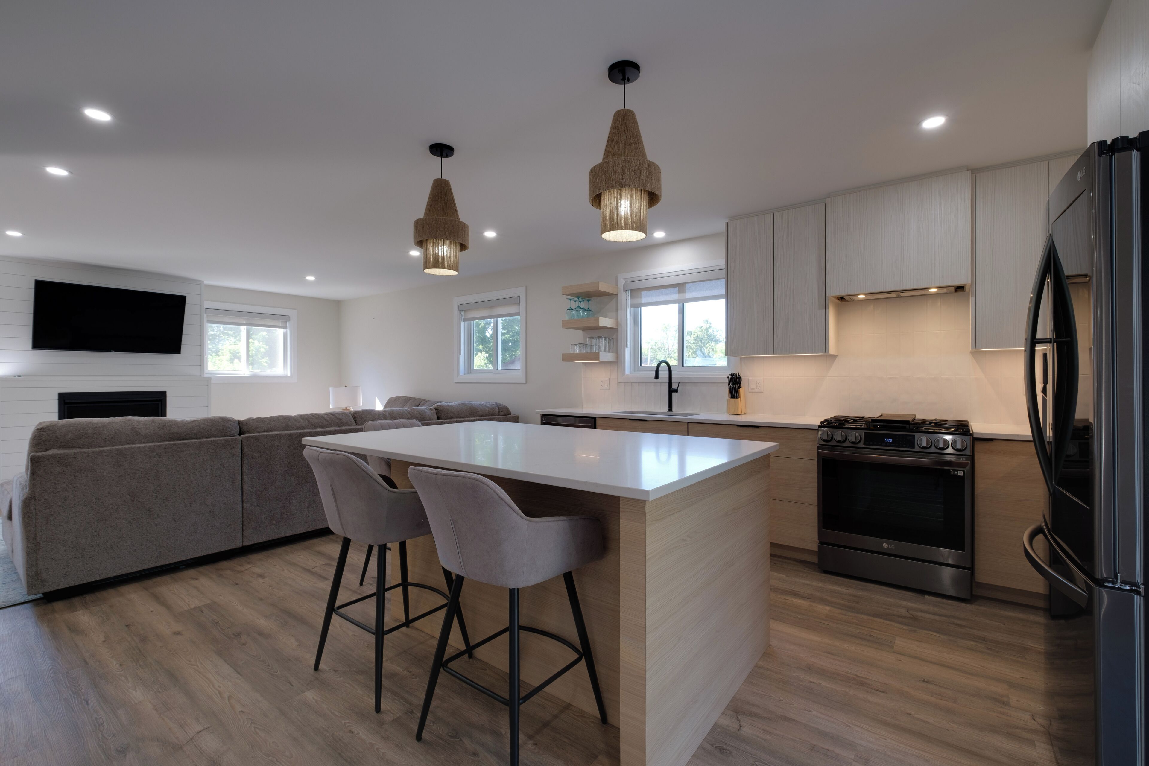 A modern kitchen with a central island, bar stools, a built-in oven, and a refrigerator.