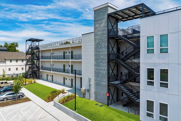 A multi-story building with external fire escapes, a parking lot, and a well-maintained lawn. - Colorful 4BR w/ Artful Design, Dining & Easy Access to Broadway The Bloom House by Avantstay (Nashville)