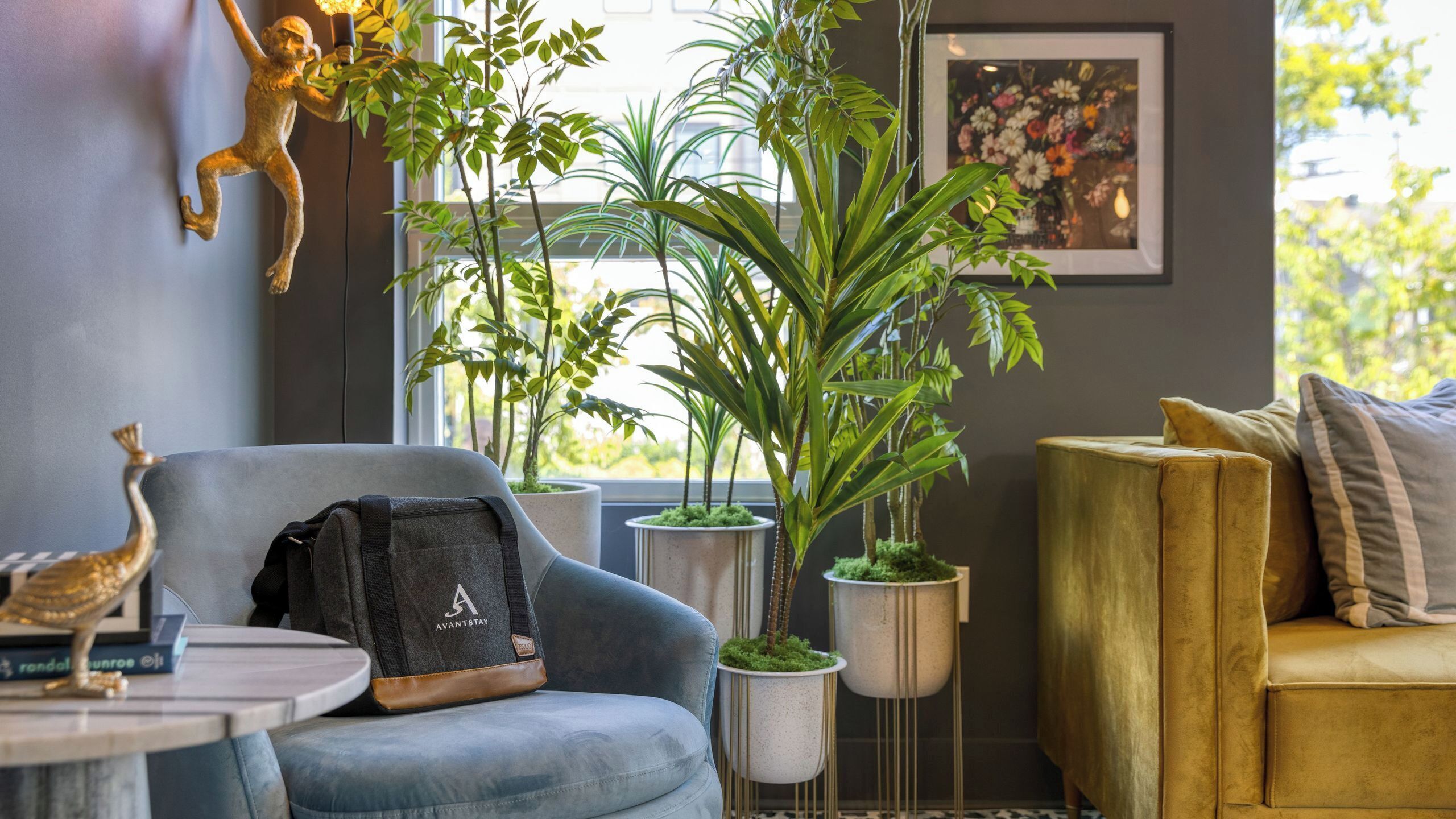 A room with a blue armchair, a gold sofa, and several potted plants.