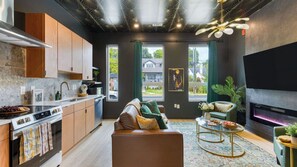 Eine moderne Küche mit Einbauofen, ein Essbereich mit Sofa und Couchtisch sowie ein Wohnzimmer mit Kamin.