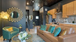 A modern living room with a sofa, coffee table, and decorative mirror. - Stylish Studio Near Broadway & East Nashville Restaurants Lischey Loft by Avantstay (Nashville)