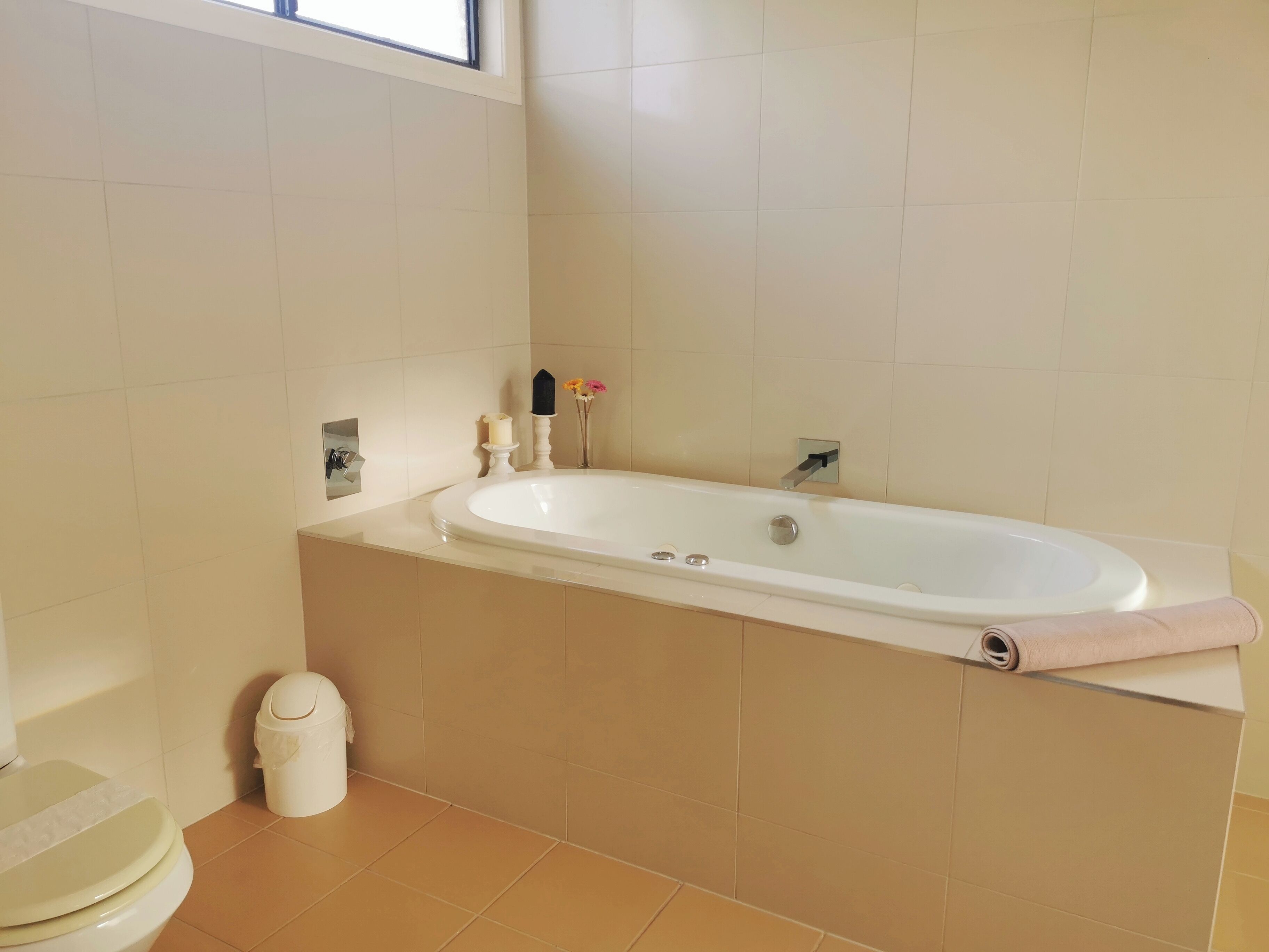 A bathroom with a bathtub, toilet, and a trash bin.