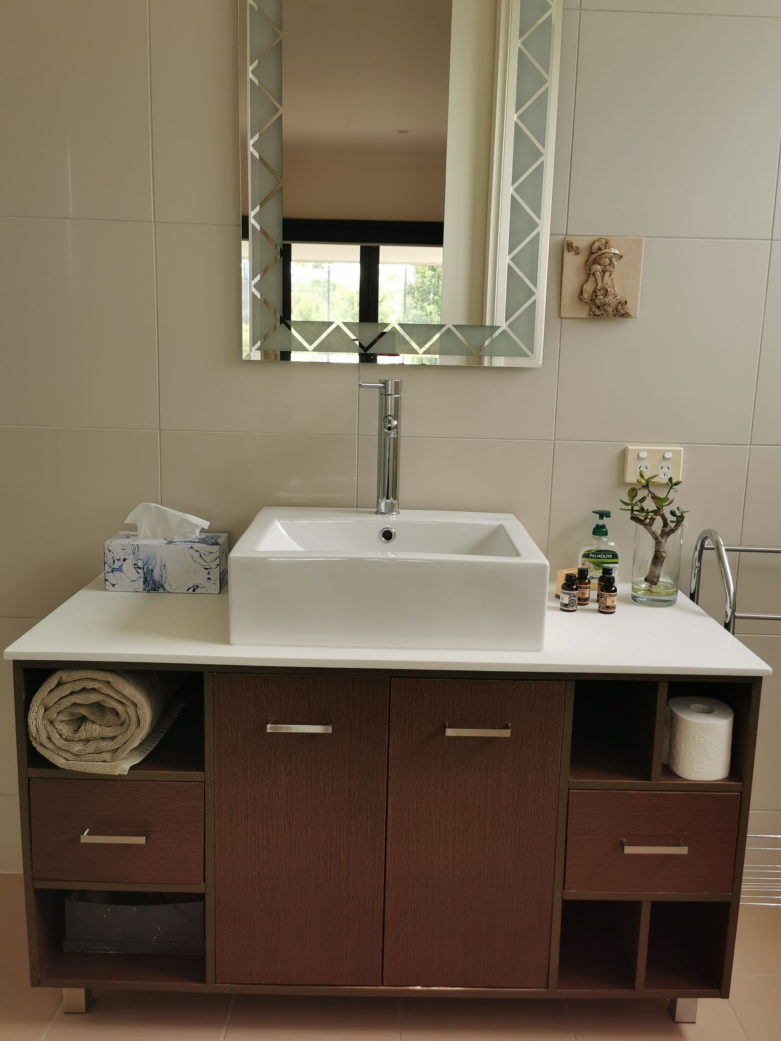A bathroom with a white sink, a mirror, and a cabinet with drawers.