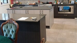 Una cocina moderna con una isla central, electrodomésticos integrados y una zona de comedor con una silla.