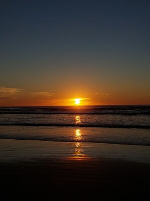 Un coucher de soleil sur l’océan, les vagues reflétant la lumière du soleil.