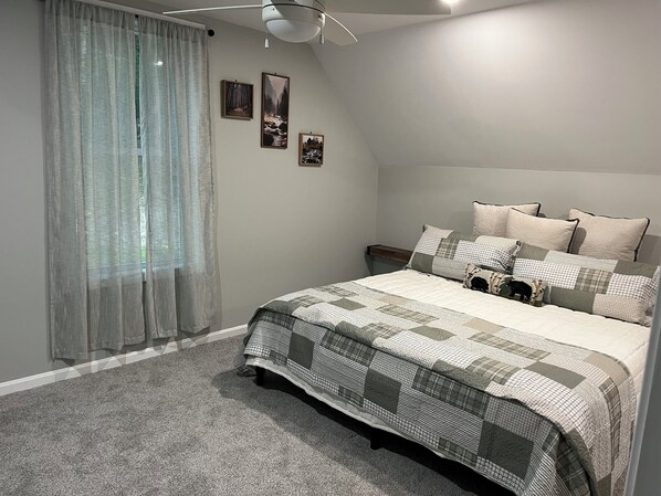 Un dormitorio con una cama, una mesita de noche, una lámpara y tres cuadros en la pared.