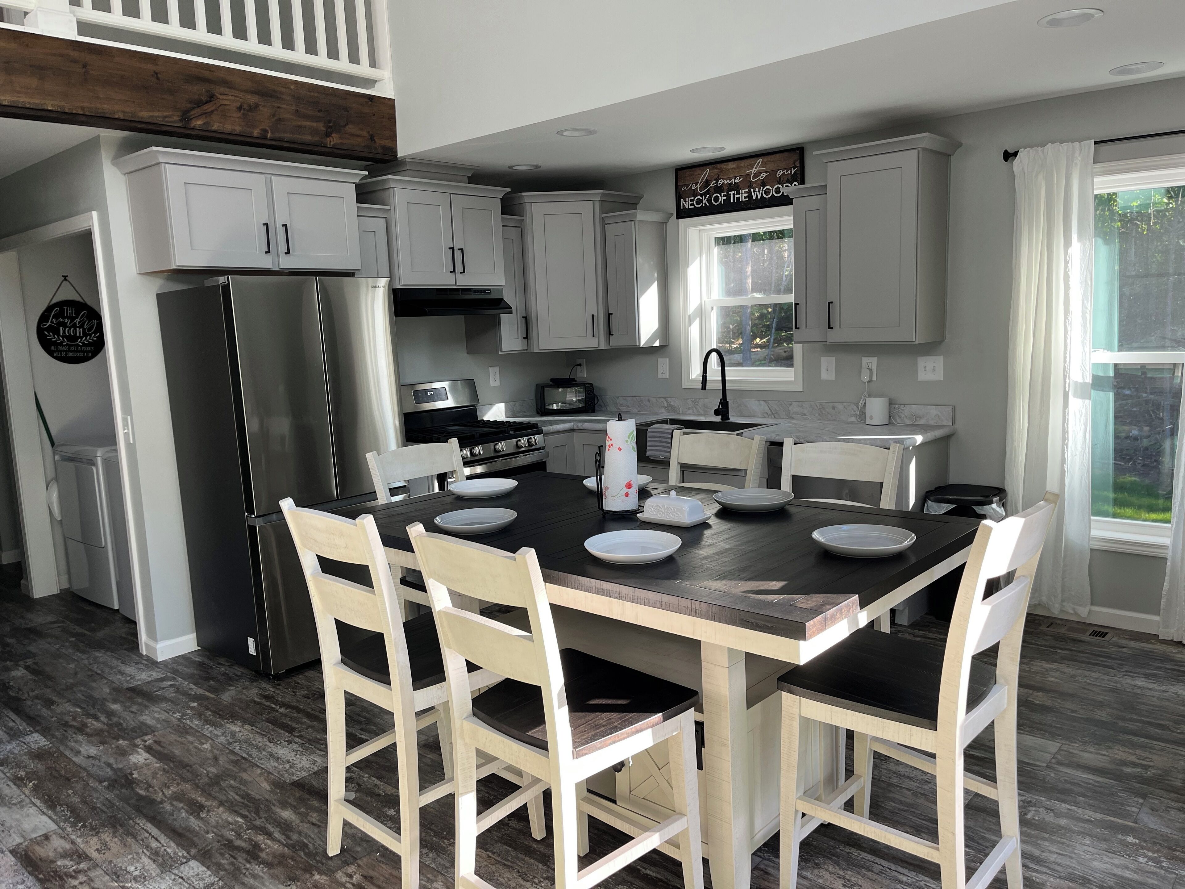 A modern kitchen with white cabinetry, a central island with seating, and a view of the outdoors through a window.