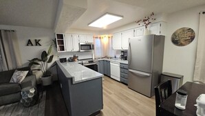 A modern kitchen with white cabinets, a built-in microwave, a stainless steel refrigerator, and a central island.