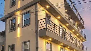 A multi-story residential building with balconies, a gated entrance, and a well-maintained lawn.