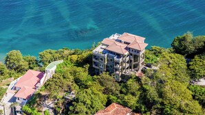 An aerial view of a multi-story building with balconies overlooking a clear blue sea. - The Only 7-Bedroom at Splendor – Luxury Oceanview Two-Level Condo with Rooftop (Playa Flamingo)
