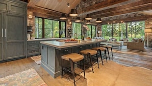 A spacious kitchen with a large island, bar stools, and a stone fireplace. - Abode at Teton Game, sweeping estate with 3 cabins (Wilson)