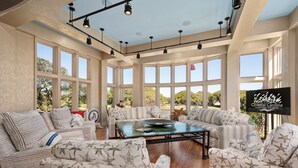 A spacious living room with large windows, a central coffee table, and striped furniture.