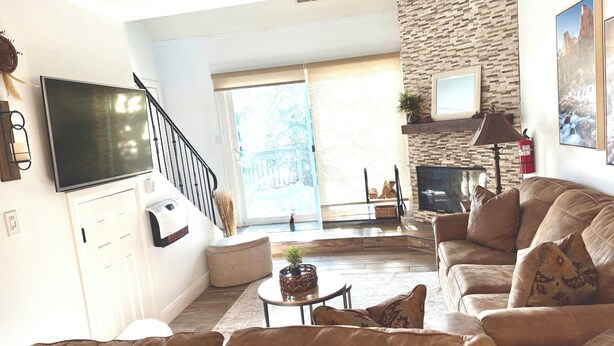 A living room with a stone wall, a fireplace, a sofa, a coffee table, and a TV.