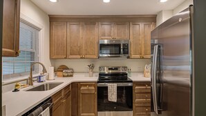 Una cocina moderna con armarios de madera, electrodomésticos de acero inoxidable y lavavajillas.