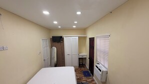 Ein Schlafzimmer mit Bett, Spiegel, Schrank, Heizkörper und einem Fenster mit Jalousien.