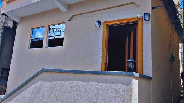 Ein zweistöckiges Gebäude mit einer beigen Fassade, einer Holztür und zwei Fenstern.