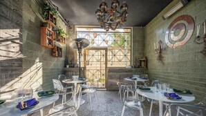 A dining area with round tables, clear chairs, and a chandelier.