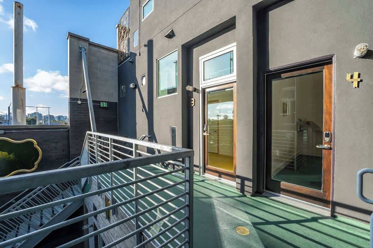A modern building with a staircase leading to an upper level, a glass door entrance, and a metal railing.