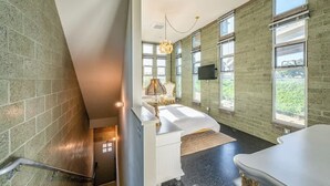 A modern bathroom with a large window, a bathtub, and a vanity with a mirror.