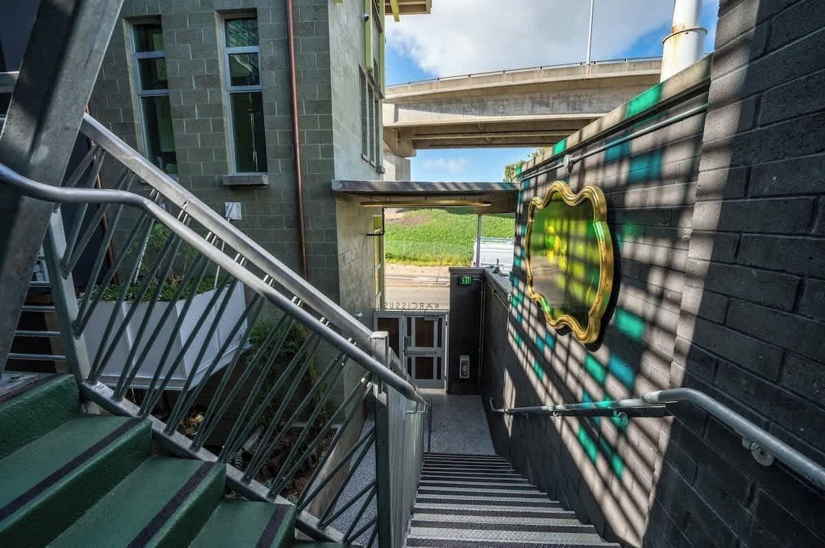 A staircase leading to a building entrance with a green and white checkered wall pattern and a metal railing.