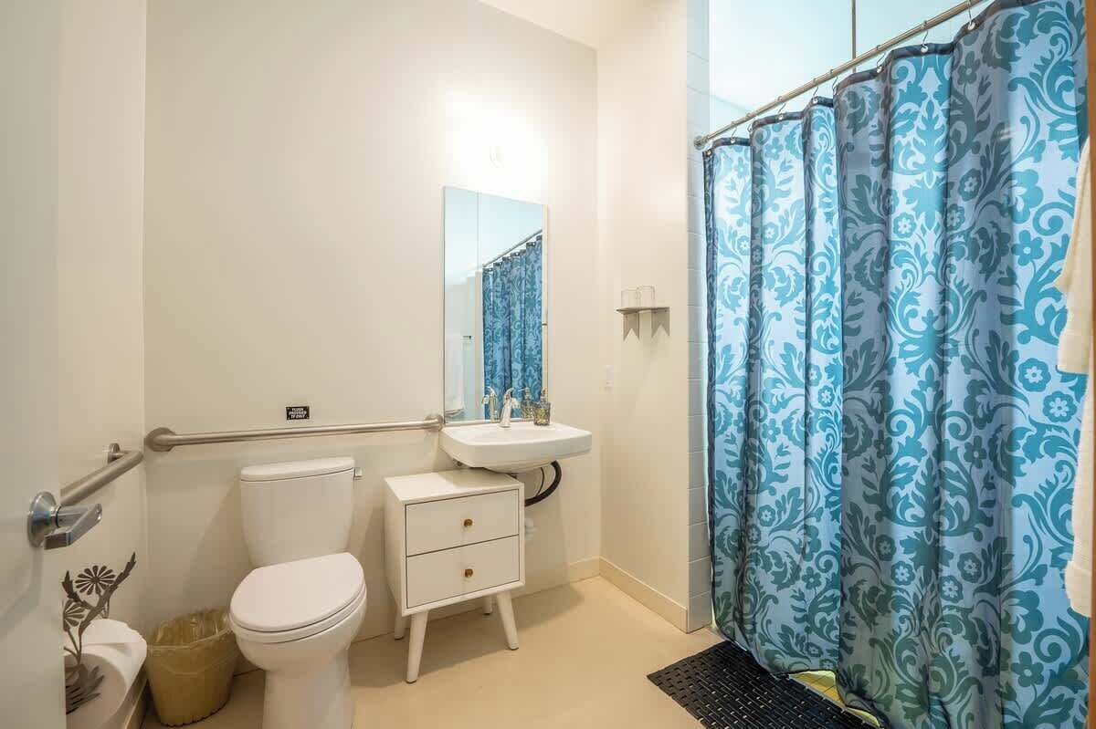 A bathroom with a toilet, sink, and shower curtain.