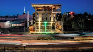 A modern building with a prominent tower and a lit entrance.